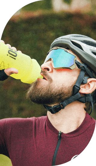 Mann mit Fahrradhelm und Sportbrille trinkt aus gelber Trinkflasche