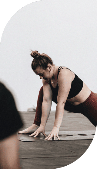 Frau mit Dutt macht Dehnübungen auf einer Yogamatte