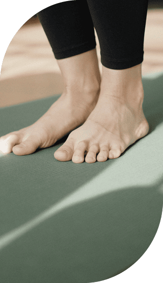 Nahaufnahme von Füßen auf einer grünen Yogamatte