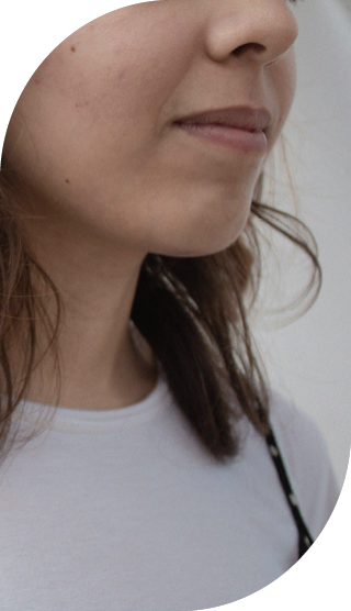 Junge Frau vor hellem Hintergrund, lächelt leicht und schaut nach rechts