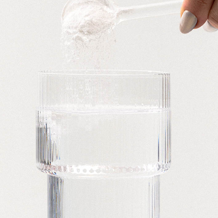 Nahrungsergänzungsmittelpulver wird von einem Messlöffel in ein Glas geschüttet