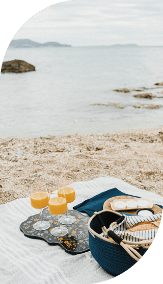 Picknickdecke am Strand mit Orangensaft, Käse und Brot