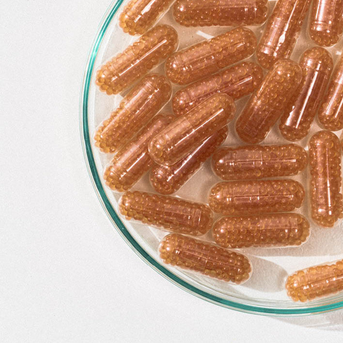 Kapseln mit braunen Kügelchen liegen in einer Glasschale