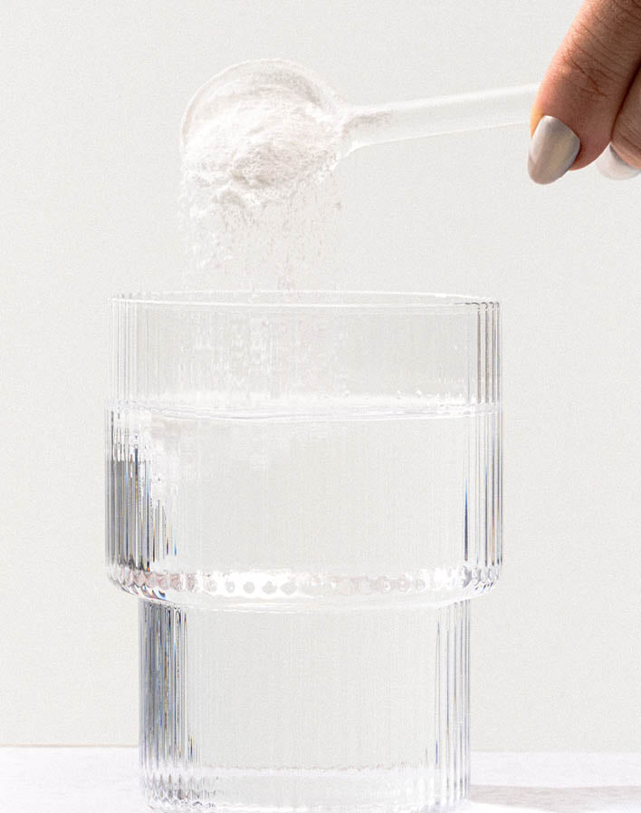 Nahrungsergänzungsmittelpulver wird von einem Messlöffel in ein Glas geschüttet